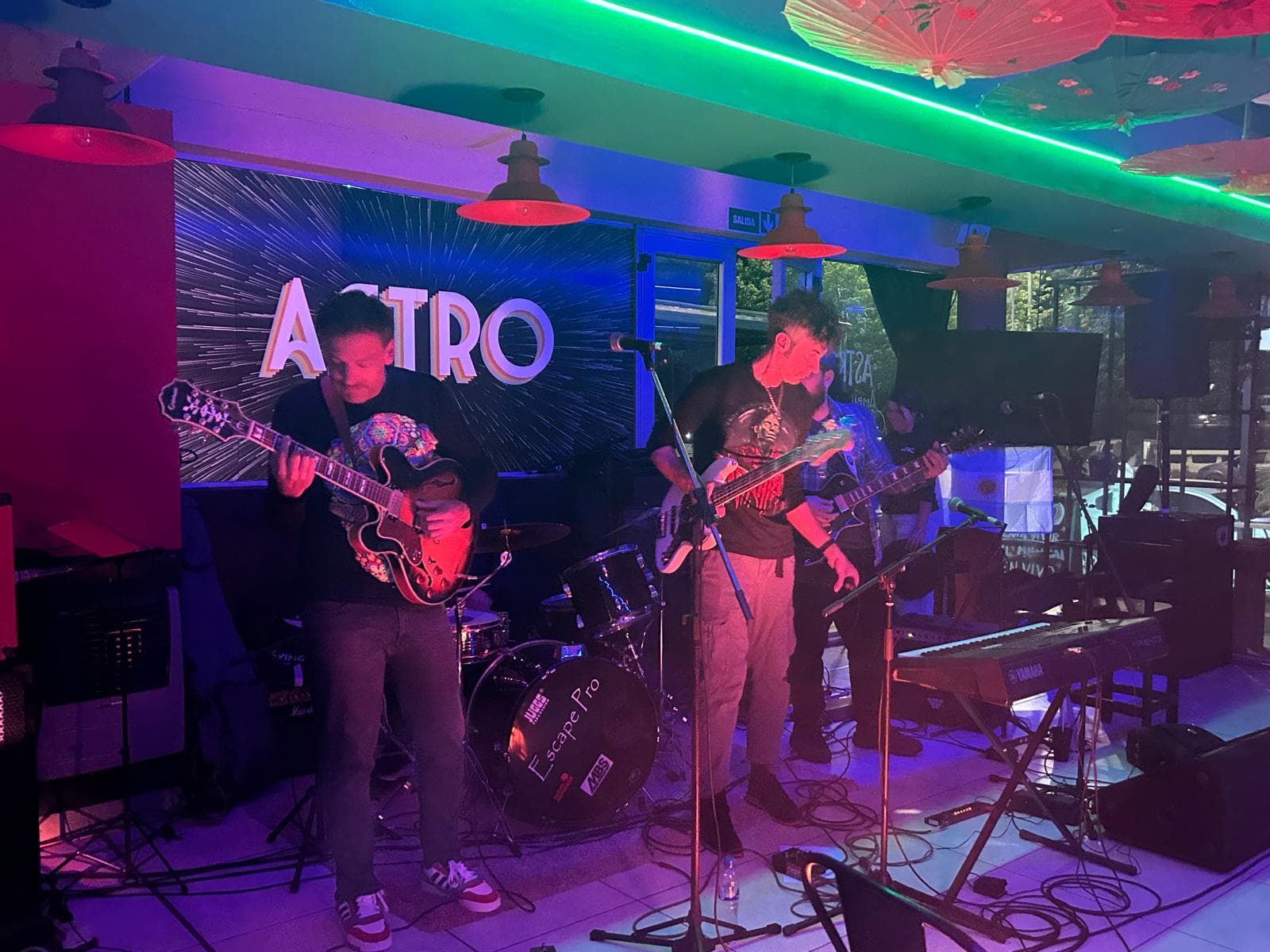 Una banda toca en vivo en un local de Federación, con guitarras, batería y teclado.
